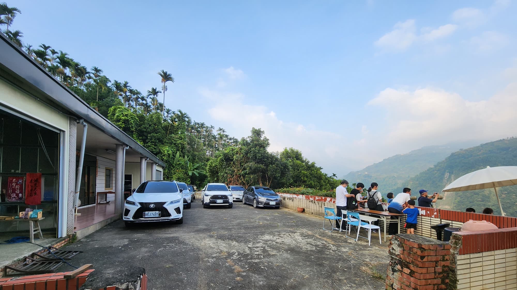 信淳茶居門口的停車空地,停著數台轎車,右側是看鳥的座位區與山谷